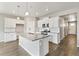 Modern kitchen featuring white cabinets, an island with a sink and wood floors at 13497 Valentia St, Thornton, CO 80602