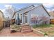 Backyard featuring a brick patio, grill, and flowering trees against the home's blue exterior at 2590 S Independence St, Lakewood, CO 80227