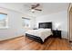 Well-lit bedroom featuring wood floors, two windows, a ceiling fan, and a dark wood bed frame with matching side tables at 3907 E 133Rd Ct, Thornton, CO 80241