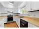 Well-lit kitchen with white cabinetry, wood countertops, stainless steel oven, and a large window overlooking the backyard at 3907 E 133Rd Ct, Thornton, CO 80241