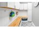 Mudroom with white cabinets, hooks, a wooden countertop, and patterned tile flooring at 8390 Coyote Dr, Castle Pines, CO 80108