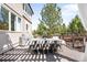 Outdoor dining area on a deck, featuring a large table and chairs with tree backdrop at 8390 Coyote Dr, Castle Pines, CO 80108