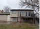 Rear exterior of a home featuring tan siding and access to a raised wooden deck with stairs at 220 Mckinley Dr, Bennett, CO 80102