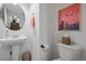 Cozy powder room features a pedestal sink, round mirror, and artwork at 9300 E Florida Ave # 1202, Denver, CO 80247