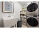 Organized laundry room with stacked washer and dryer, ample storage, and utility sink at 9300 E Florida Ave # 1202, Denver, CO 80247