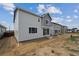 Newly built home backyard features straw-covered dirt, a walkout slider, and other new homes in the distance at 45927 Wood Thrush Ave, Bennett, CO 80102
