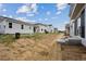New construction backyard features straw-covered dirt, newly built homes, and a bright blue sky above at 45927 Wood Thrush Ave, Bennett, CO 80102