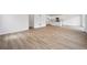 Open-concept living room with light wood flooring and white kitchen in the background at 45927 Wood Thrush Ave, Bennett, CO 80102