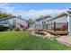 Well-maintained backyard with wooden deck, pond, lush grass, and gray siding home at 34 Skyline Dr, Wheat Ridge, CO 80215