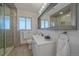 Modern bathroom with a walk-in shower, decorative mirror, white vanity, and neutral tile floors at 34 Skyline Dr, Wheat Ridge, CO 80215
