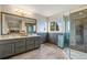 Bathroom featuring a double vanity, framed mirror, walk-in shower with glass door, and tile accent wall at 5604 S Shawnee St, Aurora, CO 80015