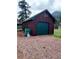 Detached garage with green door and ample space for parking, surrounded by gravel driveway at 245 Lower Glenway St, Palmer Lake, CO 80133