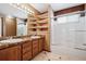 Bathroom featuring a double sink vanity, open storage shelves, and a shower with glass doors at 5395 S Flanders Way, Centennial, CO 80015