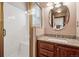 Bathroom featuring a shower, granite countertop vanity, a sink, and a large round mirror at 5395 S Flanders Way, Centennial, CO 80015