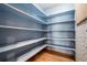 Pantry featuring wood floors, ample shelving, and an adjacent patterned wallpaper accent wall at 5395 S Flanders Way, Centennial, CO 80015