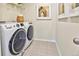 Efficient laundry room with front-load washer and dryer, tiled floor, and neutral wall art at 834 N Bently St, Watkins, CO 80137
