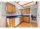 Compact kitchen with hardwood floors, white appliances, wood cabinets, and blue countertop at 13648 W 66Th Way, Arvada, CO 80004