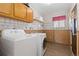 Functional laundry room with washer, dryer, and ample storage space, enhanced by charming wallpaper and natural light at 13648 W 66Th Way, Arvada, CO 80004