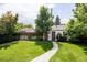 A peaceful backyard featuring green lawn, mature trees, wooden fence, and a charming pathway at 1185 S Steele St, Denver, CO 80210