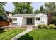 Inviting front yard featuring green lawn, a beautiful garden, and a charming white brick house at 1185 S Steele St, Denver, CO 80210