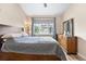 Bedroom features a wood frame bed, dresser with mirror, and window with blue curtains at 8779 S Kipling Way # 204, Littleton, CO 80127