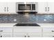 Close-up of a kitchen with stainless steel microwave and cooktop against a decorative backsplash at 3762 White Rose Loop, Castle Rock, CO 80108