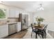 Dining area with stainless steel refrigerator, table for four, modern chandelier, and wood floors at 9054 Dover St, Westminster, CO 80021