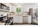 Modern kitchen with white cabinets, stainless steel appliances, and a window over the sink at 9054 Dover St, Westminster, CO 80021