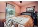 Bedroom featuring pink walls, wood trim, window, and comfortable bed at 5704 Ammons St, Arvada, CO 80002