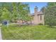 Beautifully landscaped yard with lush green lawn and mature trees surround a brick home at 5704 Ammons St, Arvada, CO 80002