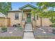 A charming brick home featuring a covered front porch with vibrant green trim and landscaping at 5704 Ammons St, Arvada, CO 80002