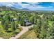 High angle aerial shot features a home with mature trees, manicured lawn, and circular driveway nestled in a green landscape at 6451 Crestbrook Dr, Morrison, CO 80465