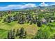 Picturesque aerial view showcases a community with homes, pools, and lush landscaping set against a mountain backdrop at 6451 Crestbrook Dr, Morrison, CO 80465