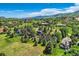 Aerial view captures homes with pools nestled amongst green lawns and lush trees, set against a mountain backdrop at 6451 Crestbrook Dr, Morrison, CO 80465