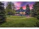Expansive backyard featuring a pool, lush lawn, mature trees and beautiful landscaping at 6451 Crestbrook Dr, Morrison, CO 80465