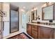 Bathroom featuring double sinks with granite countertop, wood cabinets, and a glass-enclosed shower at 6451 Crestbrook Dr, Morrison, CO 80465