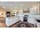Modern kitchen featuring an island, white cabinetry, stainless appliances, and stone accents near the fireplace at 6451 Crestbrook Dr, Morrison, CO 80465