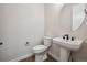 Stylish powder room featuring a modern pedestal sink and round mirror at 5549 Riverbend Ave, Firestone, CO 80504