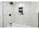 Elegant shower with marble-patterned tile and built-in shelving at 8701 Huron St # 2-106, Thornton, CO 80260