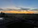 Serene backyard view with white fence, landscape, and picturesque sunset beyond the horizon at 2355 Saddle Back Ct, Fort Lupton, CO 80621