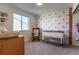 Adorable Bedroom with a crib, rocking chair, and unique patterned wallpaper at 2355 Saddle Back Ct, Fort Lupton, CO 80621