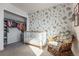 Bedroom with a floral accent wall, a white crib, and a cozy chair at 2355 Saddle Back Ct, Fort Lupton, CO 80621