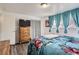 Comfortable bedroom setup with ample natural light, and wood-frame dresser with closet and TV at 1165 S Fairplay Cir # B, Aurora, CO 80012
