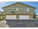 Exterior view of a two-story townhome with two garage doors and green siding at 1165 S Fairplay Cir # B, Aurora, CO 80012