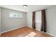 Neutral bedroom with wood floor and window featuring brown curtains at 3570 E Arapahoe Pl, Centennial, CO 80122