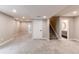 Finished basement features a neutral color scheme, plush carpeting, and access to a bathroom and staircase at 5597 S Buchanan St, Aurora, CO 80016