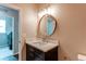 Bathroom featuring a vanity with a quartz countertop and a round mirror at 5597 S Buchanan St, Aurora, CO 80016