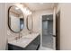 Bathroom featuring double sink vanity, oval mirrors, modern fixtures, and an open doorway at 5597 S Buchanan St, Aurora, CO 80016