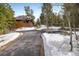 Exterior shot showing a private drive leading up to a charming wooden home surrounded by trees and snowy landscaping at 44 Linn Ln, Golden, CO 80403