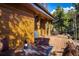 Exterior shot showcasing the wooden porch with table, wine, and chair and a wooded landscape at 44 Linn Ln, Golden, CO 80403